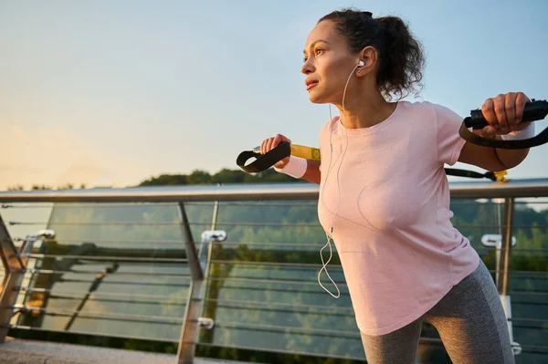 朝早く市橋で体重トレーニングを練習しながら腕や肩の筋肉の練習をしながら 一時停止ストラップ屋外で行使スポーティ女性 女性選手 — ストック写真