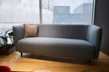 Bir mobilya mağazasının vitrininde açık pembe yastıkla sergilenen güzel minimalist stil mavi pastel kanepe.