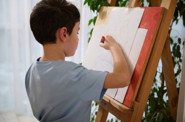 Kafkasyalı esmer okul çocuğunun evdeki çiziminin arkası. Çocuk eğitimi, eğlence, hobi, ar sınıfı, çizim, resim ve yaratıcılık kavramı