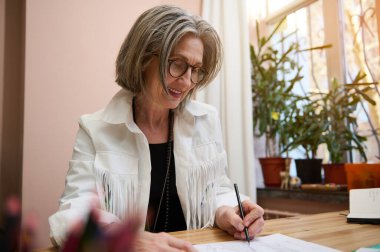 Moda tasarımcısı terzi, yaşlı Avrupalı iş kadını giysiler için eskizler çiziyor, rahat yaratıcı moda stüdyosunda yeni bir koleksiyon koleksiyonu yaratıyor.
