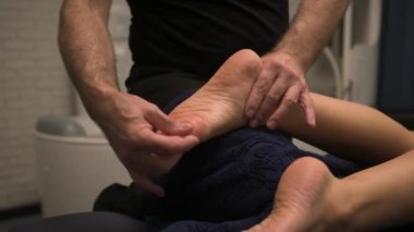 Kadın ayaklarına masaj yapan bir fizyoterapistin yakın çekimi. Masör, sağlık merkezlerinde ya da kliniklerde profesyonel ayurvedik iyileştirici stres önleyici masaj yapıyor.