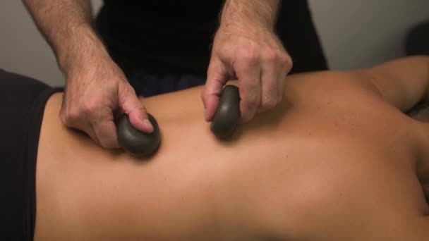 在现代健康温泉诊所 对一名按摩师的双手进行了近距离按摩 将治疗用的滚石放在妇女的背上 并进行了放松的Ayurvedic按摩治疗 身体护理概念 — 图库视频影像