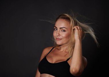 Kendine güveni tam genç Avrupalı bir kadın sağlıklı vücutlu, parlak tenli, siyah sutyenli, renkli arka planda fotokopi reklamı olan bir kadın.