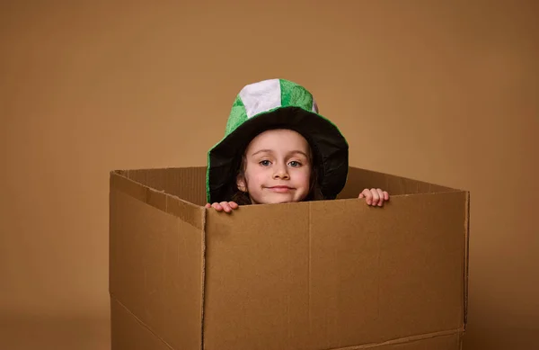 Rozkošná Čtyřletá Holčička Kloboukem Leprechaun Vykoukne Zpod Lepenkové Krabice Roztomile — Stock fotografie