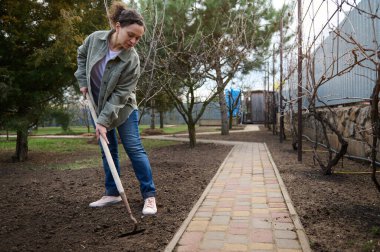 Orta yaşlı İspanyol bahçıvan bir tırmıkla toprağı gevşetiyor, baharın başında ekime hazırlıyor. Tarım, sebze bahçesi, tarım.