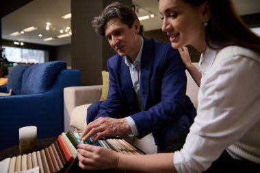 Çekici bir kadın kocasını mobilya dükkanından alışveriş yapmaya ikna eder, omuzlarını okşar, kanepe döşemesi için renkli kumaş örnekleri seçer, evdeki mobilyaların tasarımını tartışır.