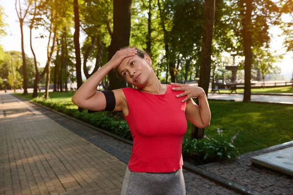 Büyüleyici bir Afrikalı Amerikalı genç sporcunun bel hizasında portresi. Spor yapan kadınlar, güneşli bir yaz gününde orman parkında çalışırken esneme egzersizleri yapıyor.