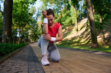 Yorgun sporcu kadın, kadın koşucu ormanda koşarken dizinde ağrı hisseder. Spor sakatlığı, diz ağrısı, spor konsepti.