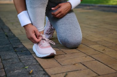 Kadın bir atlet, spor ayakkabılarına ayakkabı bağlayan bir koşucu şehir parkının koşu bandında koşuya hazırlanıyor. Spor, aktif yaşam tarzı konsepti