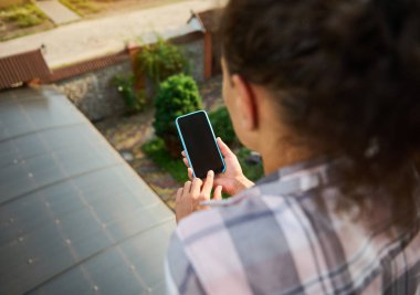 Balkondaki bir kadının elinde boş ekranda reklam alanı olan akıllı bir telefona odaklanın. Yakın plan kadın cep telefonunun boş ekranını işaret ediyor
