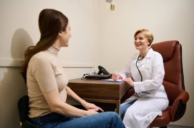 Genç beyaz kadın hasta bir doktorla randevusu var, hastanede pratisyen hekim.