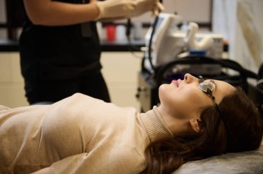 Koruyucu ultraviyole gözlük takan beyaz bir kadının portresi. Sağlık merkezindeki lazer cilt yenileme prosedüründen önce.