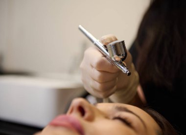 Metal donanım kozmetolojisi aletiyle güzellik uzmanının eline odaklanmak, ölü deri hücrelerinin alınması için gaz-sıvı oksijen epidermal soyulan epidermal etkili bir işlem uygulamak,