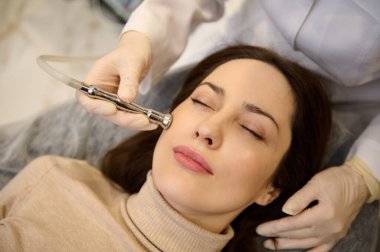 Çekici, orta yaşlı Avrupalı bir kadının güzellik kliniğinde dinlenirken bir kozmetik uzmanı tarafından cilt bakım tedavisi görmesi. Cilt bakımı ve güzellik tedavi kavramı