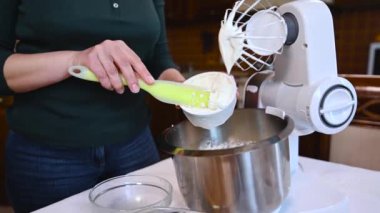 Pasta şefinin silikon spatula kullanıp krem şanti ile karıştırmak için paslanmaz bir yemek makinesinin çelik kasesine krem peynir koyduğu yakın plan. Adım adım tatlı tiramisusu için krema hazırlıyorum.