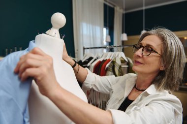 Olgun Kafkas kadın moda tasarımcısı, terzi yeni bir koleksiyonun mavi gömleğini dener elbise tasarımı ve terzilik atölyesinde.