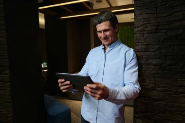 Gri saçlı, şık, orta yaşlı, sıradan giyimli Avrupalı bir adam. Perakende satış asistanı. Dijital tablet kullanan iç mimar.