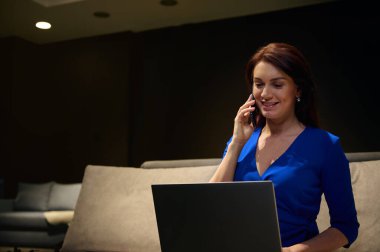 Kafkasyalı başarılı bir orta yaşlı kadın iç tasarımcının portresi dizüstü bilgisayar ve internet kullanıyor, cep telefonuyla konuşuyor. Birden fazla iş yapan kadın girişimci. Başarılı iş konsepti.