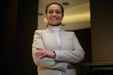 Başarılı Afrikalı Amerikalı iş kadını, girişimci, satış temsilcisi, başarılı menajer, profesyonel iç mimar kameraya çapraz kollarla poz veren dişlek gülümseme.