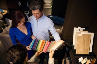 Üst düzey bir çift mobilya mağazasından alışveriş yapıyor, ev dekorasyonu ve döşenmiş mobilya yenileme projesi için kumaş örnekleri seçiyor. İç tasarım ve konut projesi kavramı