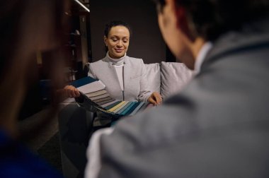 Bulanık müşterilerden kadın tezgahtara, satış görevlisine, iç mimar tasarımcıya kanepe döşemesi ve restorasyon için renkli kumaş örnekleri sunan palete bakın. Ev dekorasyonu kavramı