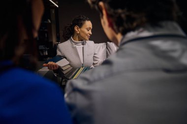 Hoş, çok ırklı genç bir satış elemanı, perakende satış görevlisi, iç tasarım galerisinde katip müşterilere kanepe restorasyonu ve döşeme için kumaş örnekleri gösteriyor. Ev geliştirme kavramı