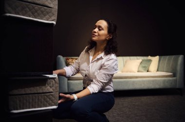 Çekici bir kadın, tasarımcı, perakende danışmanı, satış müdürü, perakendeci, depo çalışanı bir standa ortopedik yatak örnekleri serer. Mobilya dükkanı, ev tasarımı konsepti, sağlıklı uyku.