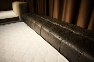 Mobilya galerisinde ortopedik şilteli rahat bir deri yatak. Yatak odası, yatak odası ve iç mimari konsepti.