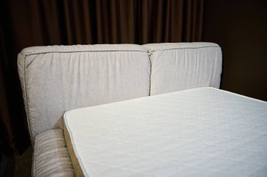 Mobilya tasarım galerisinde satılık ortopedik döşeği olan bej döşemeden yapılmış rahat ve şık döşeğin kısmi görüntüsü. Yatak odası iç tasarımı