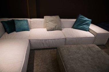 Modern bir mobilya mağazasının vitrininde sergilenen yeşil yastıklı bej bir kanepenin döşenmesi. Kısmi görünüm