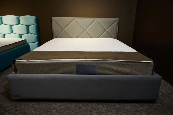 Comfortable modern stylish gray double beds with orthopedic hard mattresses, displayed for sale in the showroom of a furniture store