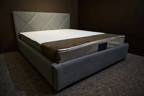 A comfortable modern stylish gray ouble beds with orthopedic hard mattresses, displayed for sale in the showroom of a furniture store