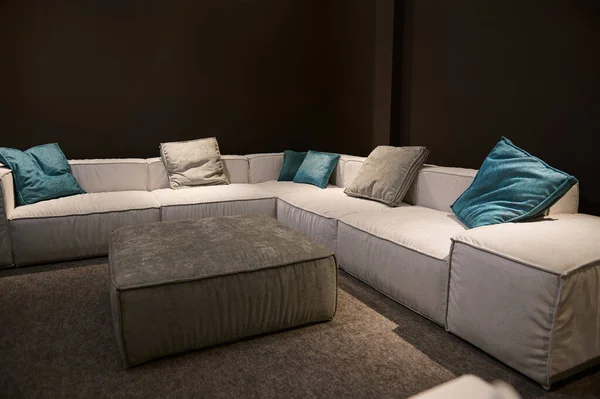 Upholstered furniture displayed for sale in showroom of furniture store. Modern stylish sofas, couches and settees with bright colored cushions from high quality fabrics in the interior design studio
