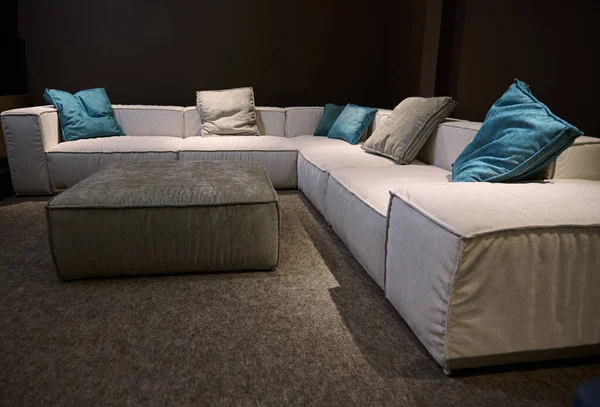 Modern stylish beige sofa with bright colored cushions from high quality fabrics in the exhibition hall. Home design concept. Upholstered furniture displayed for sale in showroom of furniture store.