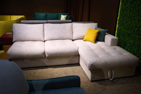 Upholstered furniture displayed for sale in the showroom of furniture store. Modern stylish sofas, couches and settees with bright colored cushions from high quality fabrics in the exhibition hall.