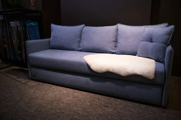 家具デザインストアでの販売のためのディスプレイ上のミニマリスト快適な青紫色のソファと毛布 ホームインテリアデザインコンセプト — ストック写真