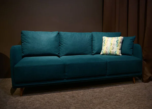 Stylish, modern and comfortable green sofa bed with green and beige cushion displayed for sale in the upholstered furniture design showroom