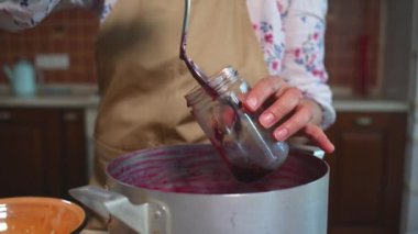 Yakın plan. Kısırlaştırılmış cam kavanozlara taze üzümlü reçel koyan şefin marmelatçısı. Ev yapımı marmelat, reçel, konserve yiyecek, kış mevsimi için reçel..