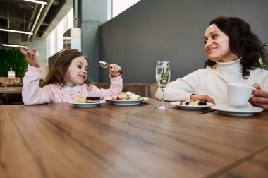 Mutlu bir anne ve tatlı kızı havaalanı restoranında abur cubur yerken, uçakla seyahat ederken, VIP kantinde otururken ve uçağa binmek için beklerken.
