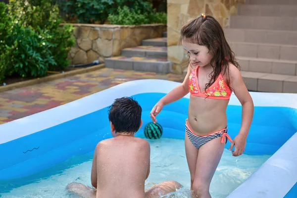 Adorable Little Girl Plays Her Brother Inflatable Water Pool Happy — Zdjęcie stockowe