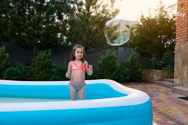 Charming Little Girl Bathing Suit Catches Soap Bubbles She Blows — Zdjęcie stockowe