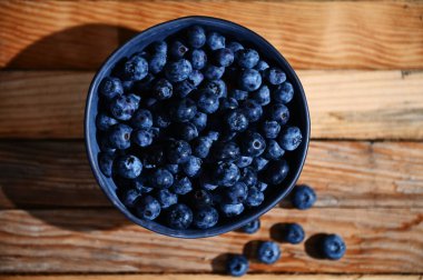 Düz yatıyordu. Ahşap bir arka planda mavi seramik bir kase taze, olgun ve yenmeye hazır yabanmersininin yatay bileşimi. Organik tarım, sağlıklı beslenme. Durgun hayat. Uzayı metin için kopyala. Pankart