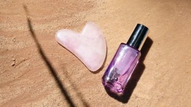 Durgun hayat. Ev masajı, yüz gerdirme ve lenfatik drenaj masajı için Gua-sha masajı ve açık mor cam bir kavanozda yaşlanmama önleyici bir serum.