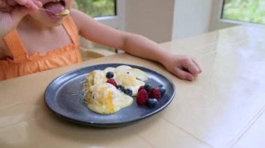 Staedicam shot: Plate with melting balls of mango ice cream sorbet, topped with berries and adorable little girl eating it, while relaxing in veranda, overlooking beautiful garden on a hot summer day