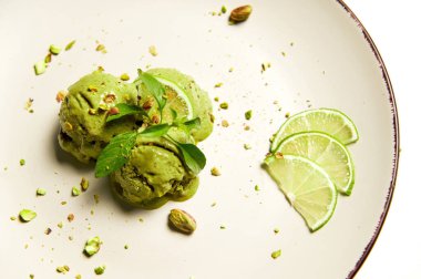 Flat lay. Refreshing ice cream. Scoops of healthy raw vegan sorbet topped with juicy lime, pistachio, green lemon basil leaf. Food still life isolated on white background. Summer concepts. Copy space
