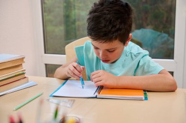 Handsome smart schoolboy using compass for drawing, draws circle while doing math and geometry homework. Back to school in new semester of the academic year. Online education concept. Homeschooling