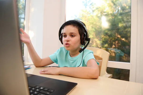 New format for homeschooling. Open to new knowledge in the new semester of academic year. Schoolboy in wireless headphones watching online video lesson, studying remotely from anywhere in the world