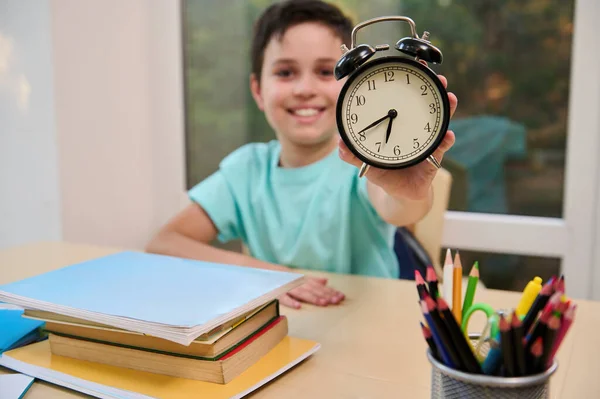 Focus Black Alarm Clock Hand Cheerful Smiling Schoolboy Sitting Desk — Fotografia de Stock