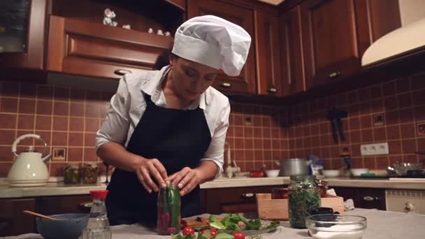 Delightful Multiethnic Woman White Chefs Cap Black Apron Filling Can — 图库视频影像