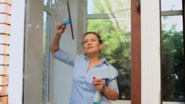 View through the streaks of glass cleaner detergent on the veranda windows to a housewife or maid washing the windows on an early spring sunny day. Professional cleaning service. Household chores